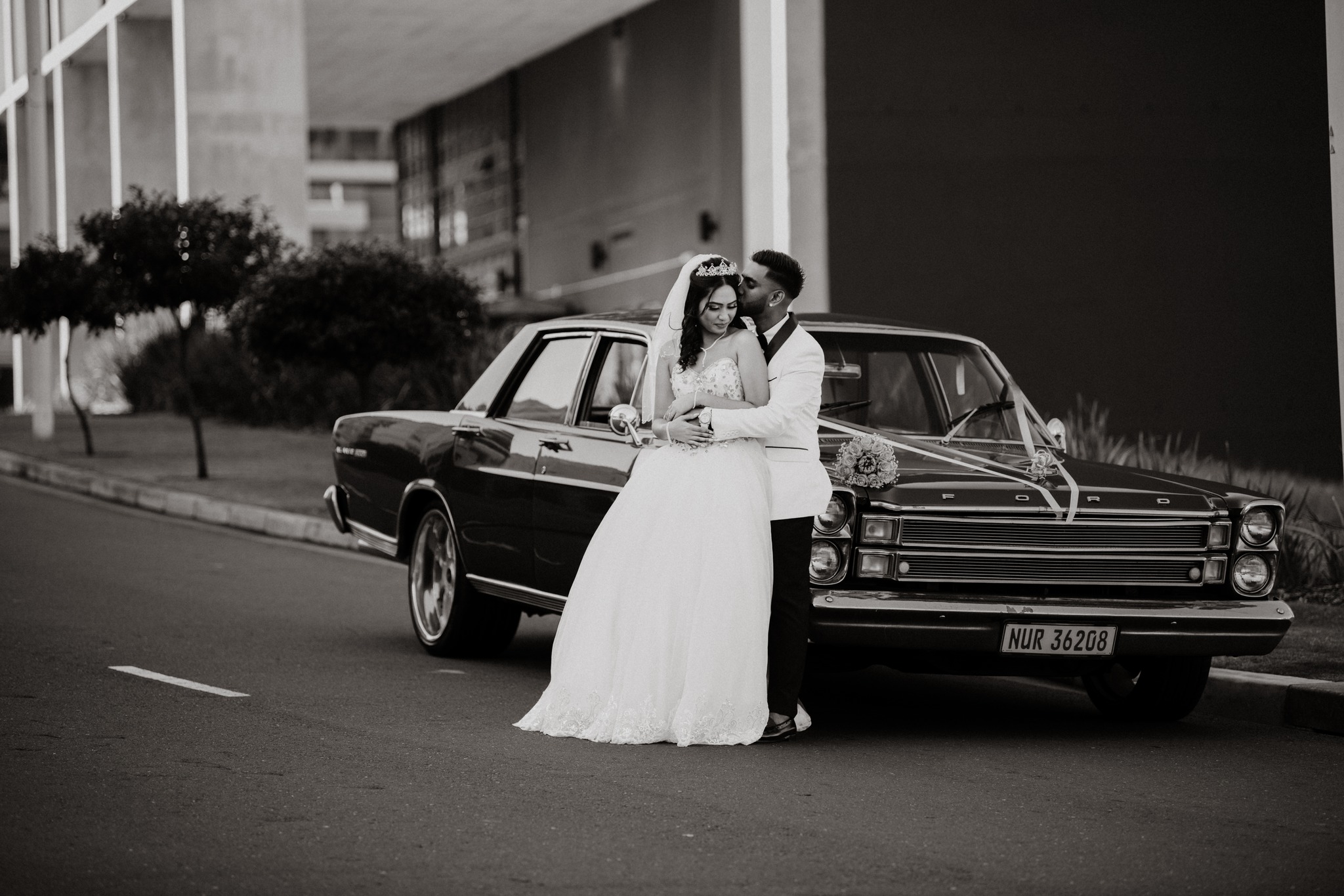  newly weds leaning on car 