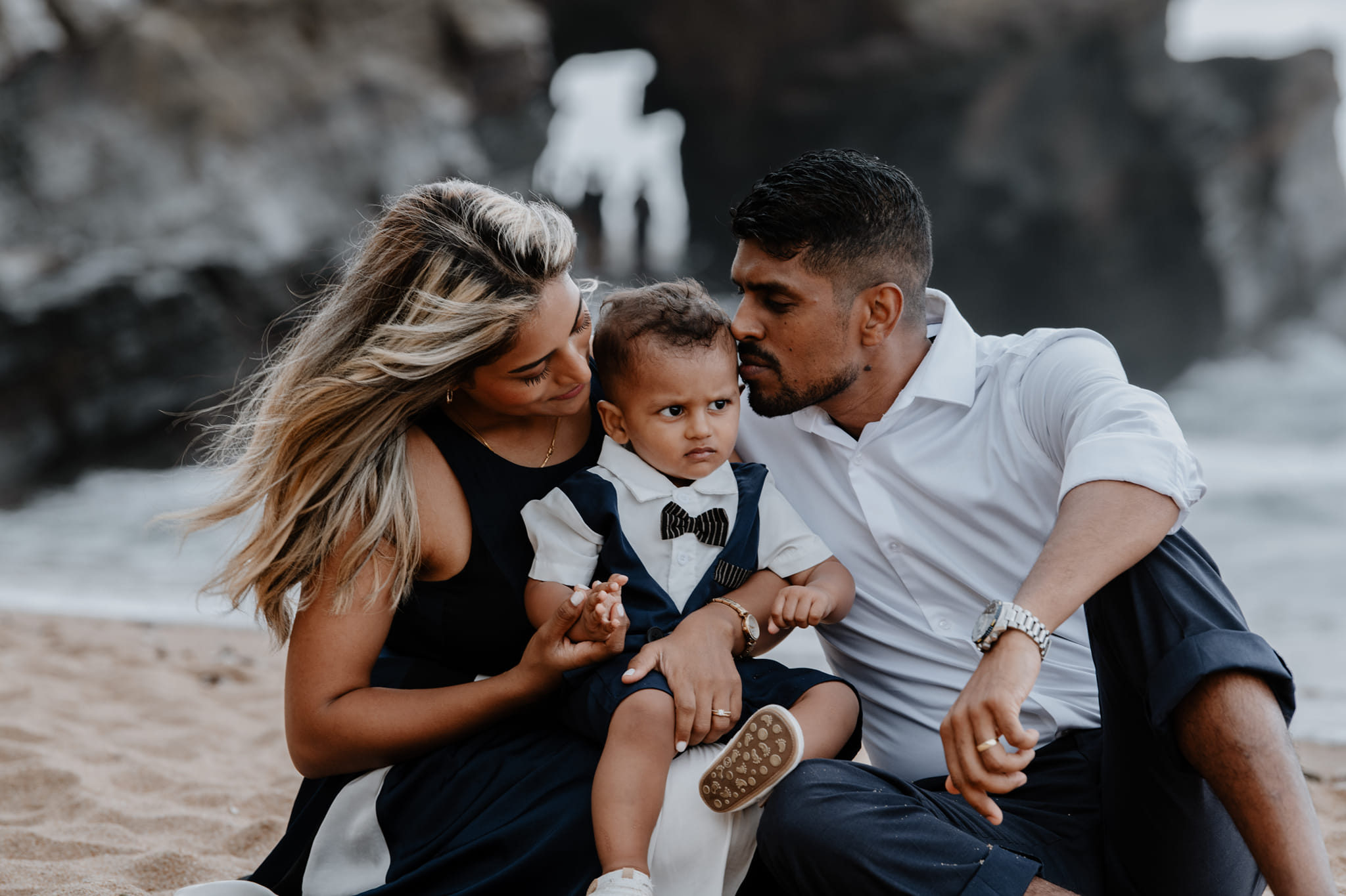  family embracing child which sitting on beach 