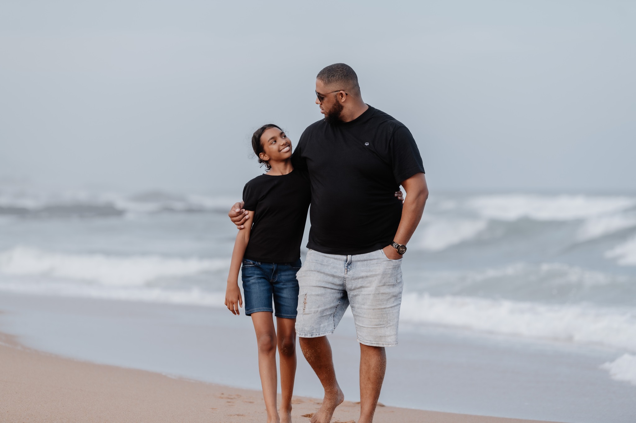  father and daughter walking on beach 