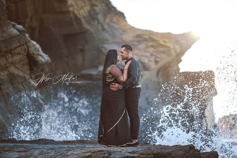  couple embrace as waves splash behind 